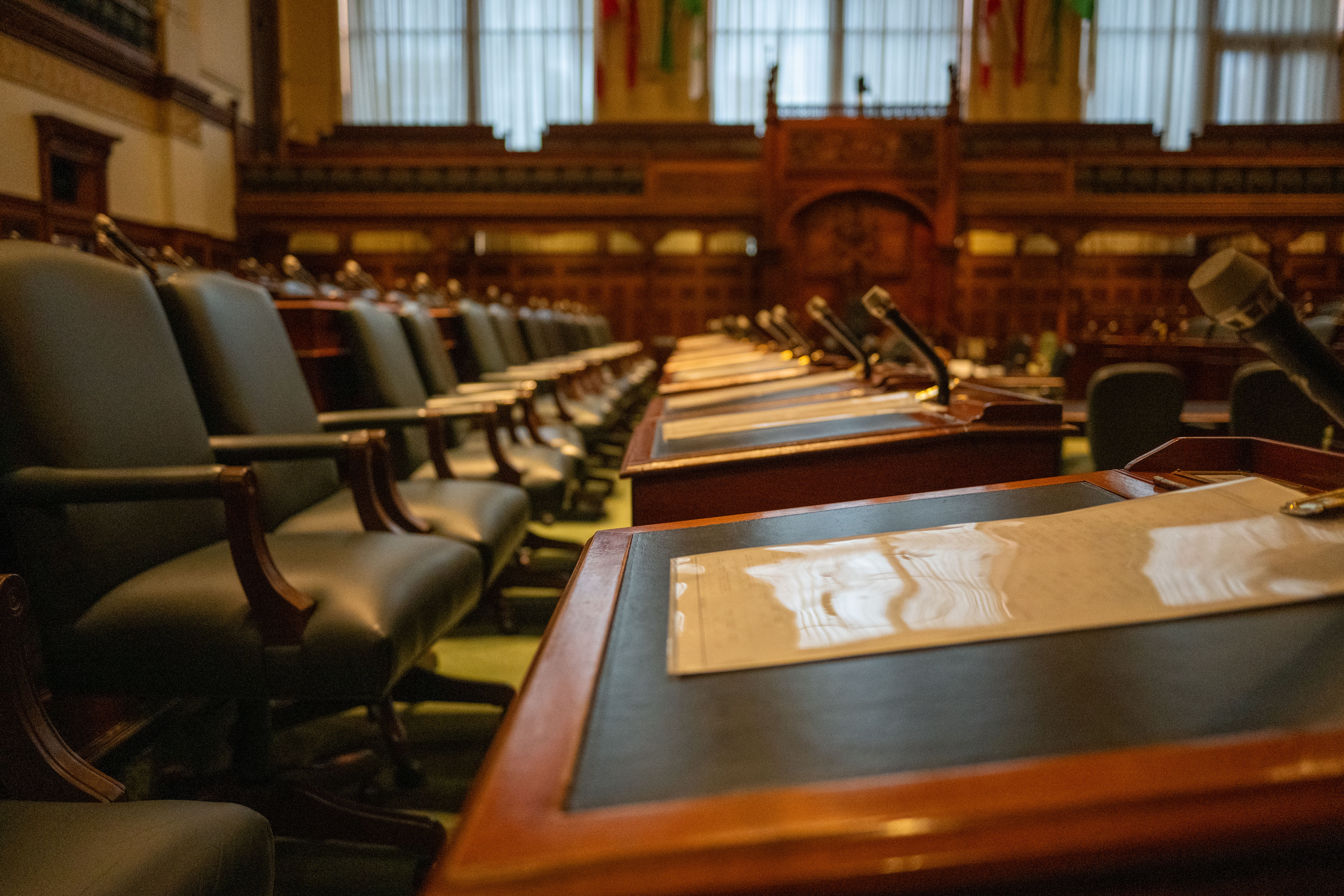 An empty legislative chamber with rows of desks and microphones