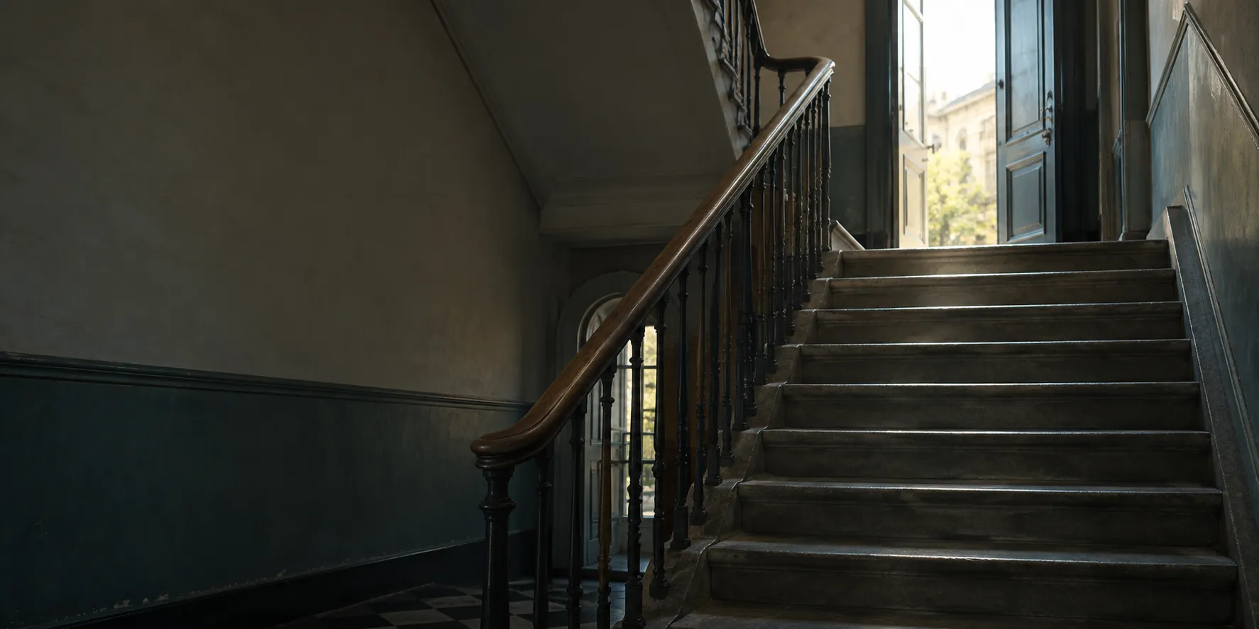 A stairwell in a public building with light coming from an open door at the top.
