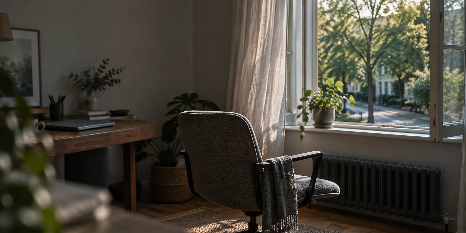 An office chair turned to face an open window, a plant on the sill.